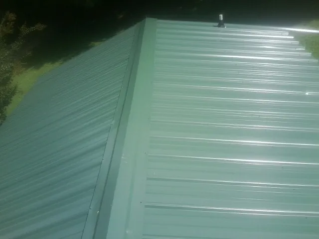 New green metal panels meeting at the ridge of a roof — Flat Roof Repair work by our crew in Cassandra