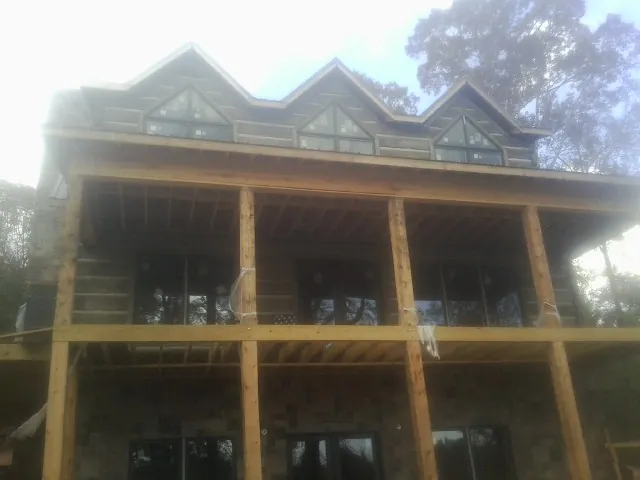 Dormers and porch framing on a large log home under construction — Roof Coating work by our crew in Cassandra