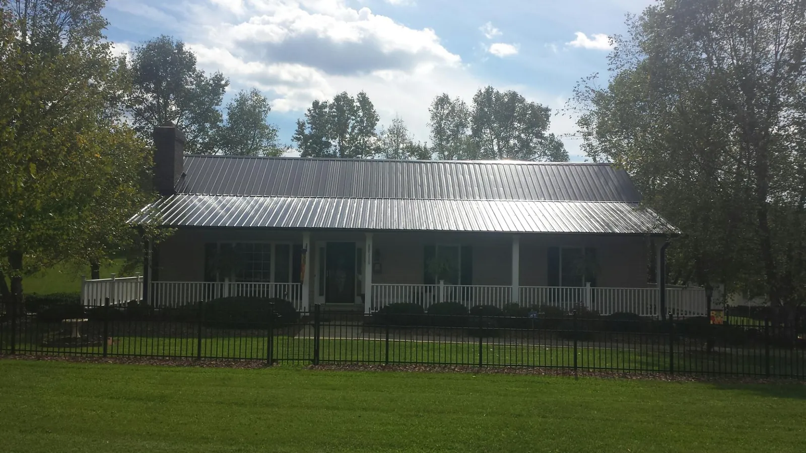 Gray metal roof on a brick ranch with a full width front porch — Gutter Guard Installation work by our crew in Cassandra
