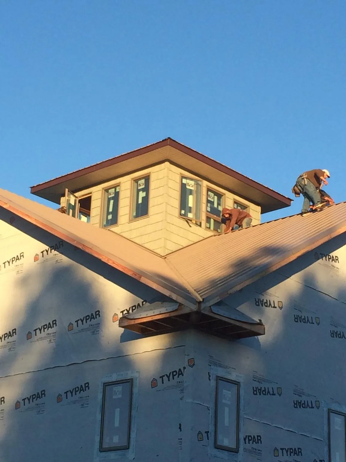Roofers working around a rooftop cupola on a new metal roof at sunset — Roof Waterproofing in Cassandra by Roofing Brothers